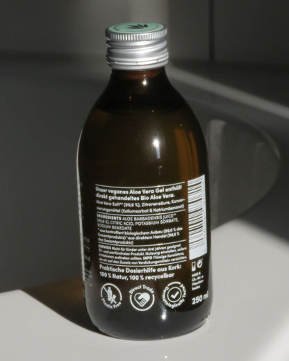 Aloe-Vera Gel in Glasflasche auf Badewanne von hinten
