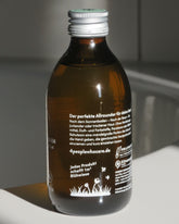 Aloe-Vera Gel in Glasflasche auf Badewanne von der Seite
