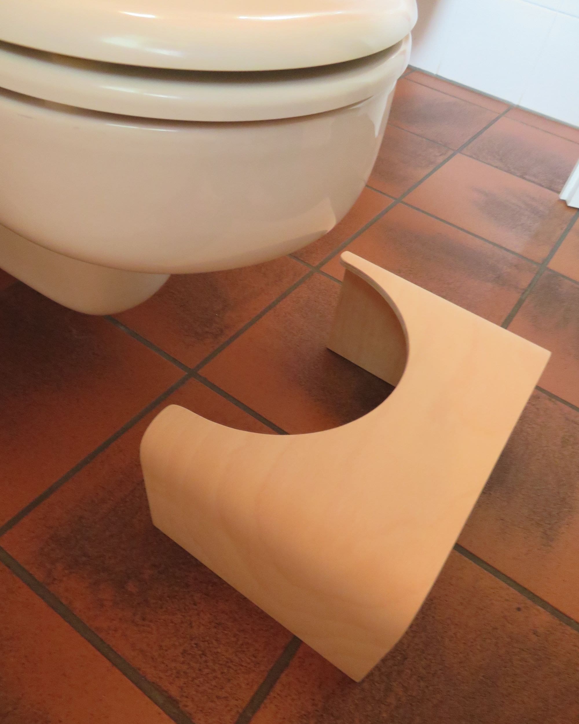 Toilettenhocker aus Holz stehend vor Toilette